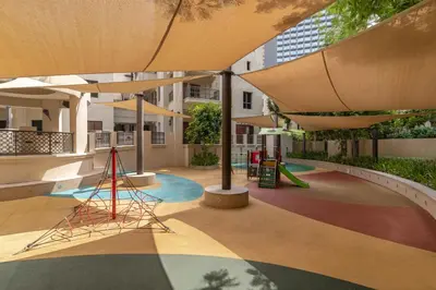 a courtyard with a playground with a large umbrella at Yansoon 7,Oldtown-Downtown - 2BR & Maids Room - Allsopp&Allsopp in Dubai