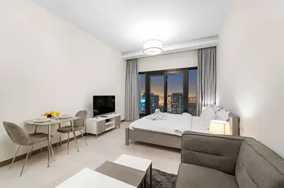 a bedroom with a bed and a table and a couch at Chic Studio Near Burj Khalifa, Dubai Opera & Dubai Mall with City Skyline Views in Dubai