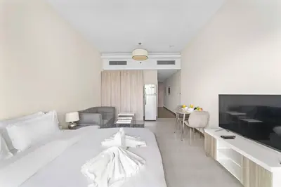 a white bedroom with a large bed and a living room at Chic Studio Near Burj Khalifa, Dubai Opera & Dubai Mall with City Skyline Views in Dubai