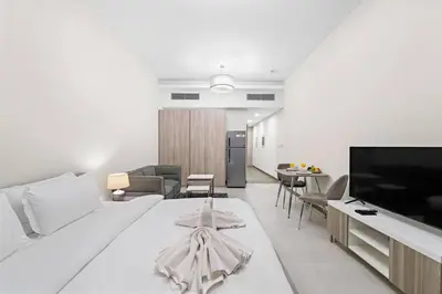a living room with a white bed and a living room with a tv at Chic Studio Near Burj Khalifa, Dubai Opera & Dubai Mall with City Skyline Views in Dubai