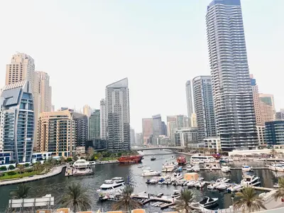 a river with boats in a city with tall buildings at Luxury One Bedroom Apartment In Dubai Marina in Dubai