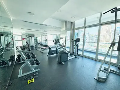 a gym with cardio equipment in a large room with windows at Luxury One Bedroom Apartment In Dubai Marina in Dubai