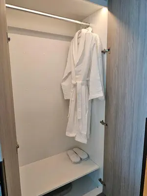 a closet with white robe and slippers in it at Spacious Studio MeDoRe Tower in Dubai