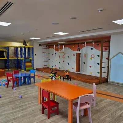 a classroom with tables and chairs and a climbing wall at Spacious Studio MeDoRe Tower in Dubai
