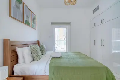 a white bedroom with a large bed and a window at ShoresInn - Cozy 1BHK in Dubai Marina in Dubai