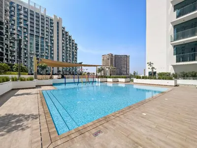 a large swimming pool in a city with tall buildings at Stunning Studio w Pool & Gym in Dubai