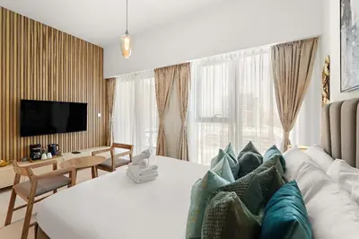 a hotel room with a white bed and a television at Stunning Studio w Pool & Gym in Dubai