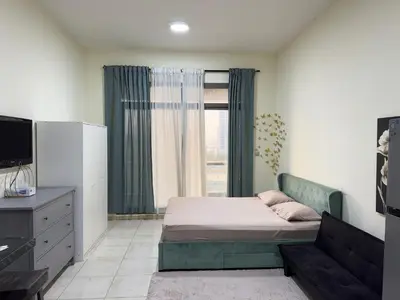 a bedroom with a bed and a tv and a window at Bright Spacious Apartment in Dubai Sports City in Dubai