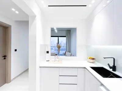 a white kitchen with white cabinets and a sink at Chic 1-BR Apt & Balcony in Binghatti Heights in Dubai