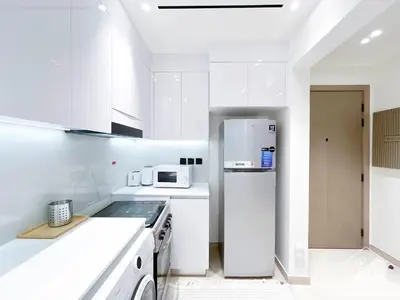 a kitchen with white cabinets and a refrigerator at Chic 1-BR Apt & Balcony in Binghatti Heights in Dubai