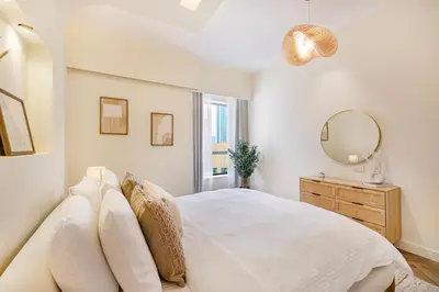 a white bedroom with a bed and a mirror at Daniels 2BR at Rimal JBR with Marina View in Dubai