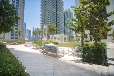 a park with benches and trees and tall buildings at Luxury Living in Emaar Beachfront w Private Beach in Dubai