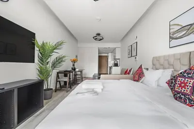 a white bedroom with a large bed and a living room at Spacious Studio In Prime Location in Dubai