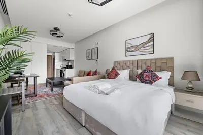 a bedroom with a large white bed and a living room at Spacious Studio In Prime Location in Dubai