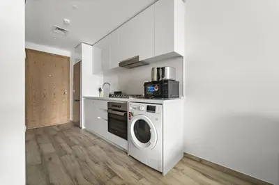 a kitchen with a washing machine and a microwave at Spacious Studio In Prime Location in Dubai