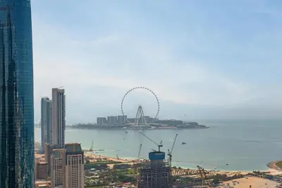 a city with a ferris wheel in the water at The Luxe Marina Experience - Stylish 2BR with Sweeping Balcony Views for Total Relaxation in Dubai