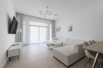 a white living room with a couch and a table at 1BD Partial Burj Al Arab View Prime Location in Dubai