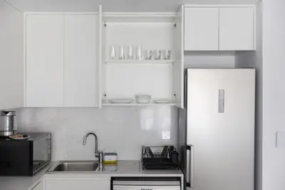 a kitchen with white cabinets and a sink and a refrigerator at 1BD Partial Burj Al Arab View Prime Location in Dubai