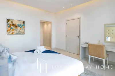 a white bedroom with a desk and a bed at LUX The Voleo Canal View Suite in Dubai