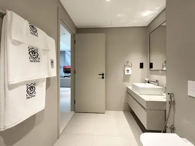a bathroom with a sink and a toilet and towels at Trophy - 1BR Beachfront Retreat w Lagoon Views in Dubai
