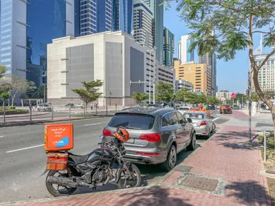 a motorcycle parked next to a car on a city street at Blueground DIFC marina view pool gym DXB-21 in Dubai