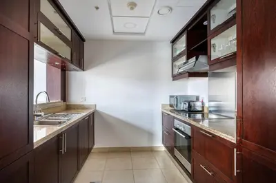 a kitchen with wooden cabinets and a sink at Blueground The Residences gym parking DXB-1348 in Dubai