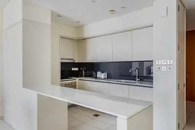 a white kitchen with white cabinets and a sink at Blueground DIFC Burj K views indoor pool DXB-1493 in Dubai