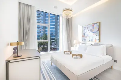 a white room with a bed and a large window at Palm Home next to Nakheel Mall with Private Beach in Dubai
