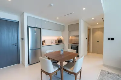a kitchen and dining room with a wooden table and chairs at Beachfront Holiday 1BR Sea Marina Views in Dubai