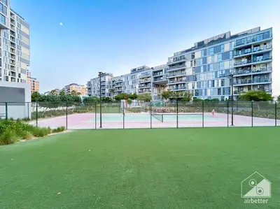 an empty tennis court with apartment buildings in the background at Luxurious 1BR Apt with Balcony in Production City in Dubai