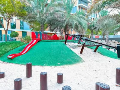 a playground in a resort with a slide and swings at Luxurious 1BR Apt with Balcony in Production City in Dubai