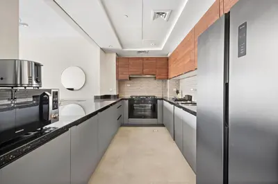 a large kitchen with white cabinets and a long hallway at Brand New 2 Br Apartment In Family Community in Dubai