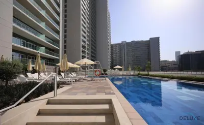 a swimming pool with chairs and umbrellas next to a building at Special Deal 2BR with Canal Views & Relaxing Balcony by Deluxe Holiday Homes in Dubai