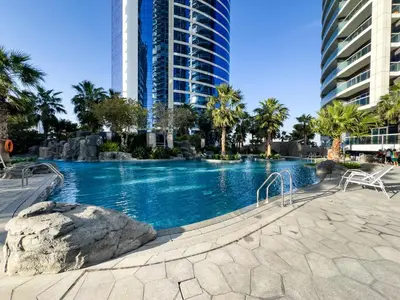 a large swimming pool with palm trees and buildings at ALiving Modern & Chic 1BR I Paramount Tower D -2203 in Dubai