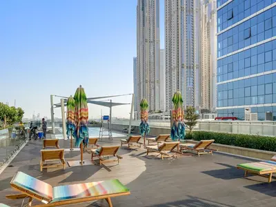 a group of chairs and umbrellas on a patio with buildings at ALiving Classy 1BR I Near Burj Khalifa & Dubai Mall I Missoni Tower- 211 in Dubai