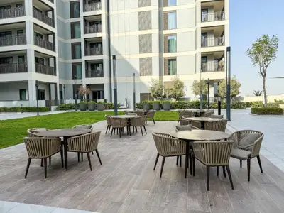a patio with tables and chairs in front of a building at Creekside Bliss 1BR with Beach Access Summer 3 in Dubai
