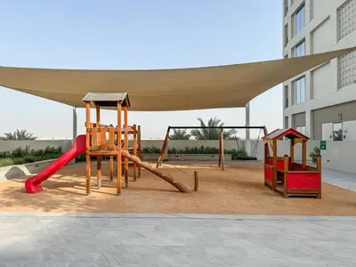 a playground with a canopy and two play equipment at Creekside Bliss 1BR with Beach Access Summer 3 in Dubai