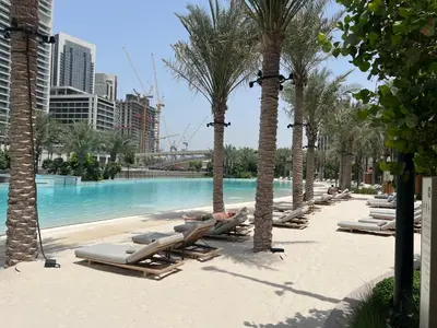 a row of chaise lounges on a beach with palm trees at Creekside Bliss 1BR with Beach Access Summer 3 in Dubai
