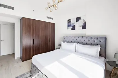 a bedroom with a large white bed and a wooden cabinet at A Living One 1BR Apartment At Asayel 3, Madinat Jumeirah in Dubai