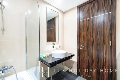 a bathroom with a sink and a wooden door at LUX The Bonnington JLT Suite 2 in Dubai