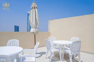 a patio with white tables and chairs and an umbrella at Royalton - Tranquil 15th-Floor Apartment with City Views in Dubai