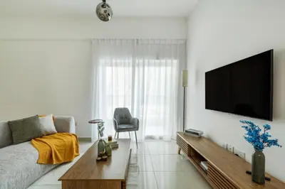 a living room with a couch and a television on a wall at ShoresInn - Elegant 1BR in Dubai Marina in Dubai