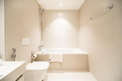 a white bathroom with a tub and a toilet at SettlerHomes - Emaar Beachfront Haven With The Sea View in Dubai