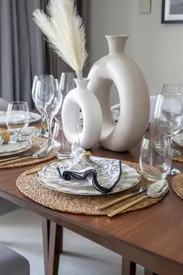 a table with white vases and plates and wine glasses at Frank Porter - Vida Creek Beach in Dubai