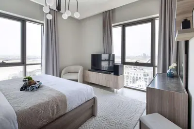 a bedroom with a bed and a tv and windows at Frank Porter - Vida Creek Beach in Dubai