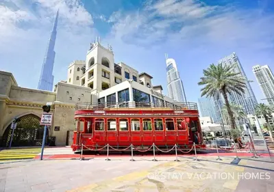 a red trolley parked in front of a building at 5 Min Walk to Burj Khalifa 2BHK Luxury Downtown Burj Haven in Dubai