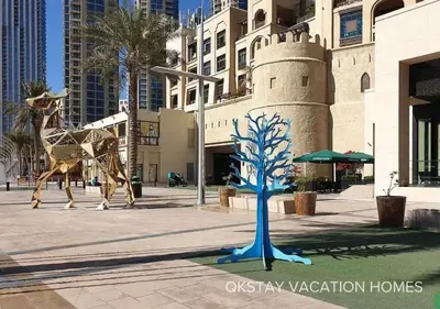 two statues of giraffes and a tree on a street at 5 Min Walk to Burj Khalifa 2BHK Luxury Downtown Burj Haven in Dubai
