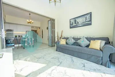 a living room with a blue couch and a kitchen at Bloomfields Modern 1bedroom In Wavez in Dubai