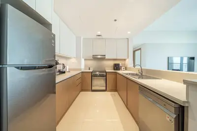 a large kitchen with a stainless steel refrigerator at LUXE | Luxury 2BR | Creek View | Modern & Cozy in Dubai