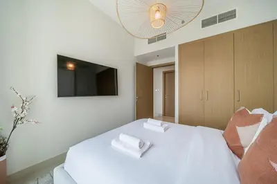 a bedroom with a white bed with two towels on it at LUXE | Luxury 2BR | Creek View | Modern & Cozy in Dubai